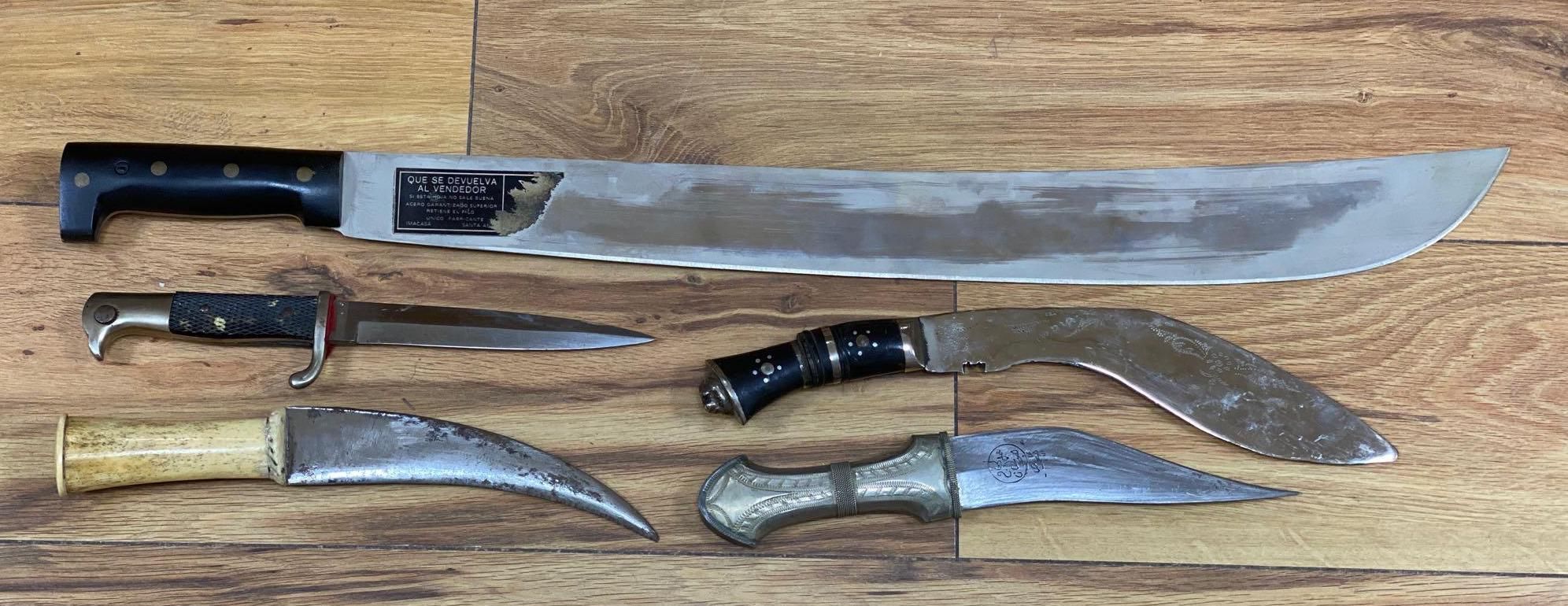 Five various weapons including a Kukri, a carved bone handled dagger with brass sun, moon and stars sheath and an El Salvador machete